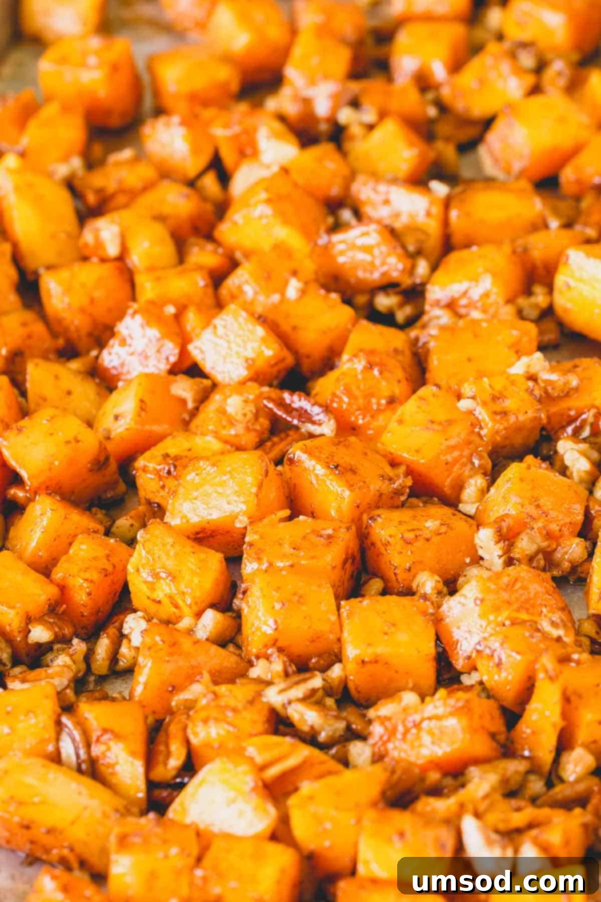 Caramelized Golden Butternut 3 Close-up view of roasted butternut squash cubes and crunchy nuts evenly spread on a baking sheet, showcasing their golden-brown edges.