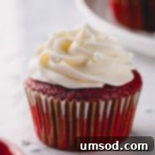 Red velvet cupcake with white cream cheese frosting, close-up.