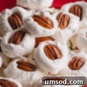 A pile of divinity with pecan halves on top on a red plate.