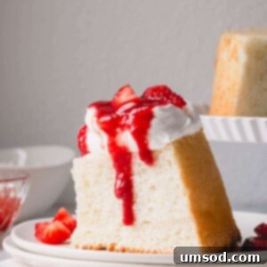 Cloud Nine Angel Food Cake 11 A slice of angel food cake topped with whipped cream and strawberry sauce.