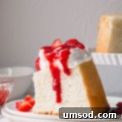 Cloud Nine Angel Food Cake 12 A slice of angel food cake topped with whipped cream and strawberry sauce, smaller version.