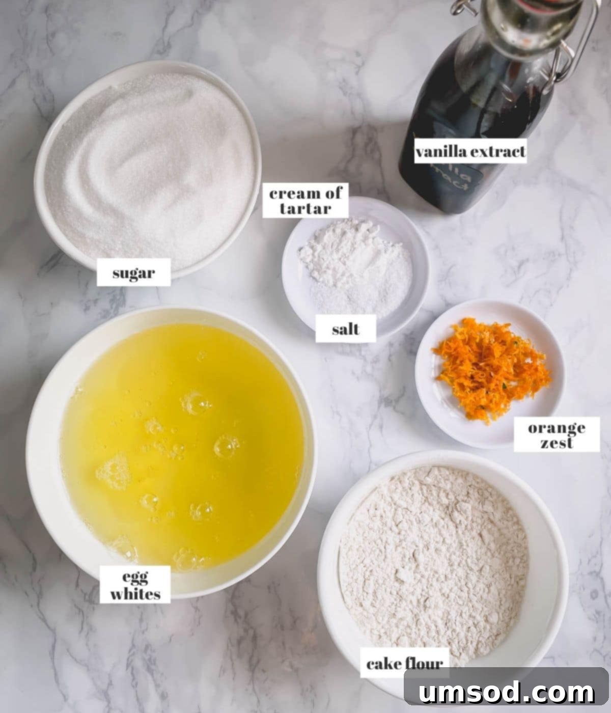 Cloud Nine Angel Food Cake 3 Ingredients laid out for making angel food cake: egg whites, cake flour, sugar, orange zest, cream of tartar, vanilla, and salt.