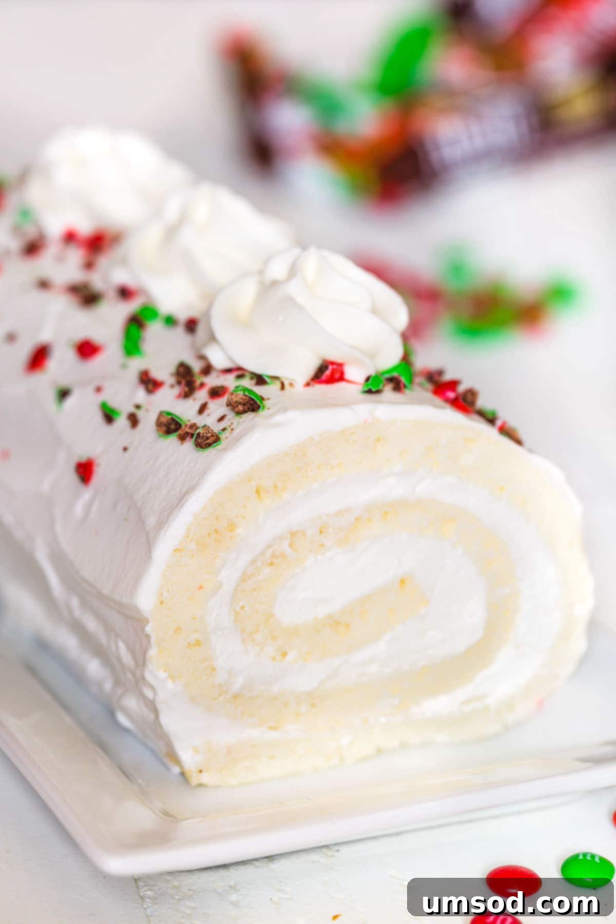 Enchanted White Swirl 2 Snow White Roll Cake topped with festive crushed red and green M&Ms, ready for holiday celebrations.