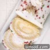 Enchanted White Swirl 11 Sliced white roll cake topped with crushed red and green M&Ms.