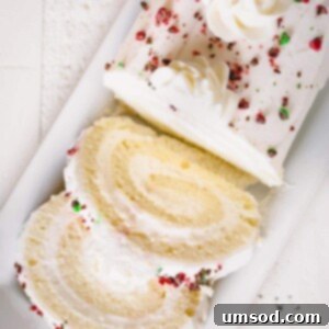 Enchanted White Swirl 10 Sliced white roll cake topped with crushed red and green M&Ms.