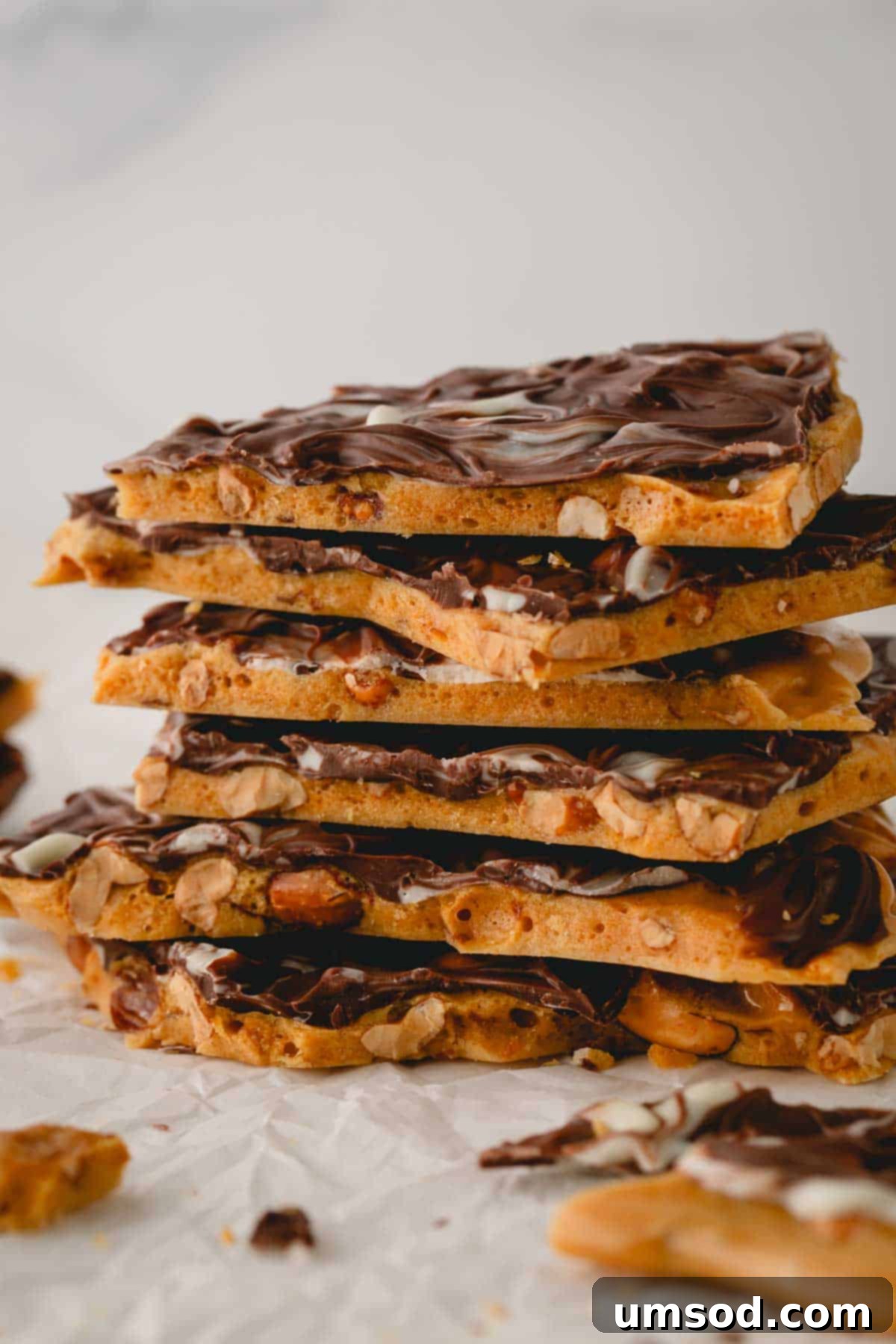 A beautiful stack of freshly made chocolate peanut brittle pieces, showcasing the glossy chocolate layer.