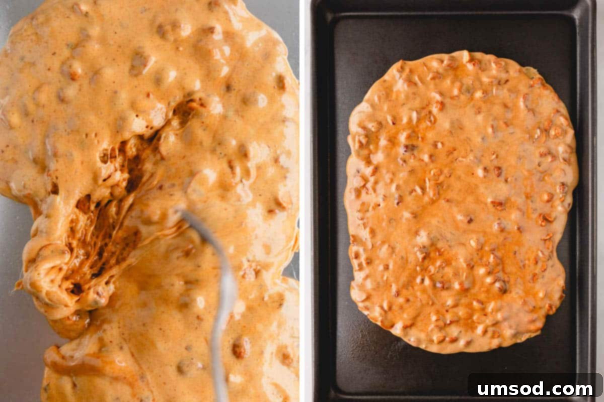 Hot peanut brittle mixture being carefully spread into a thin, even layer on a prepared baking sheet using two forks.