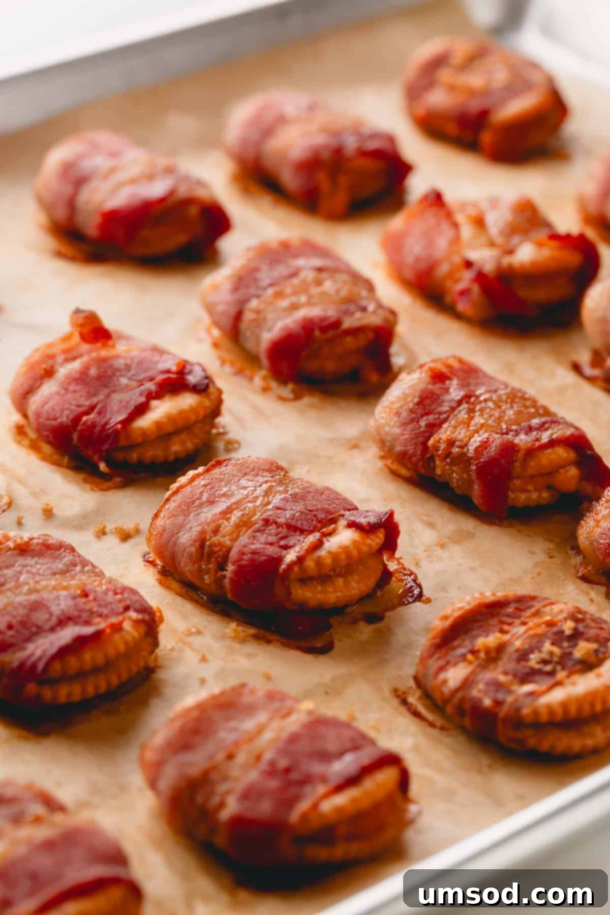 Smoky Bacon Cheese Bites 3 Bacon-wrapped crackers neatly arranged on a parchment paper-lined baking sheet, ready for the oven.