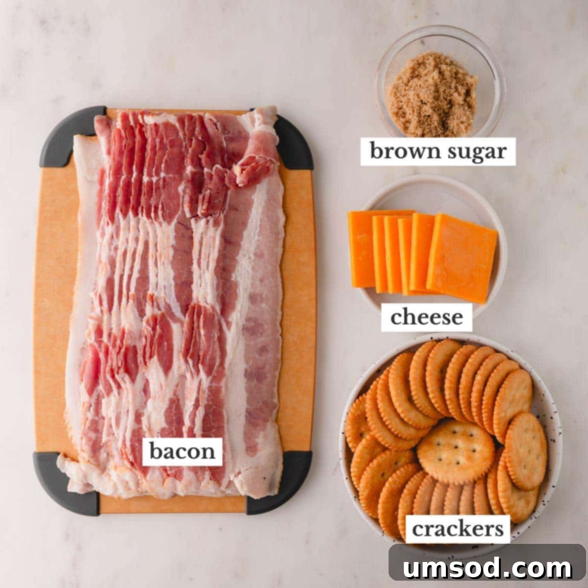 Smoky Bacon Cheese Bites 4 A flat lay of the four main ingredients: raw bacon strips, a stack of crackers, cheddar cheese slices, and a bowl of brown sugar.