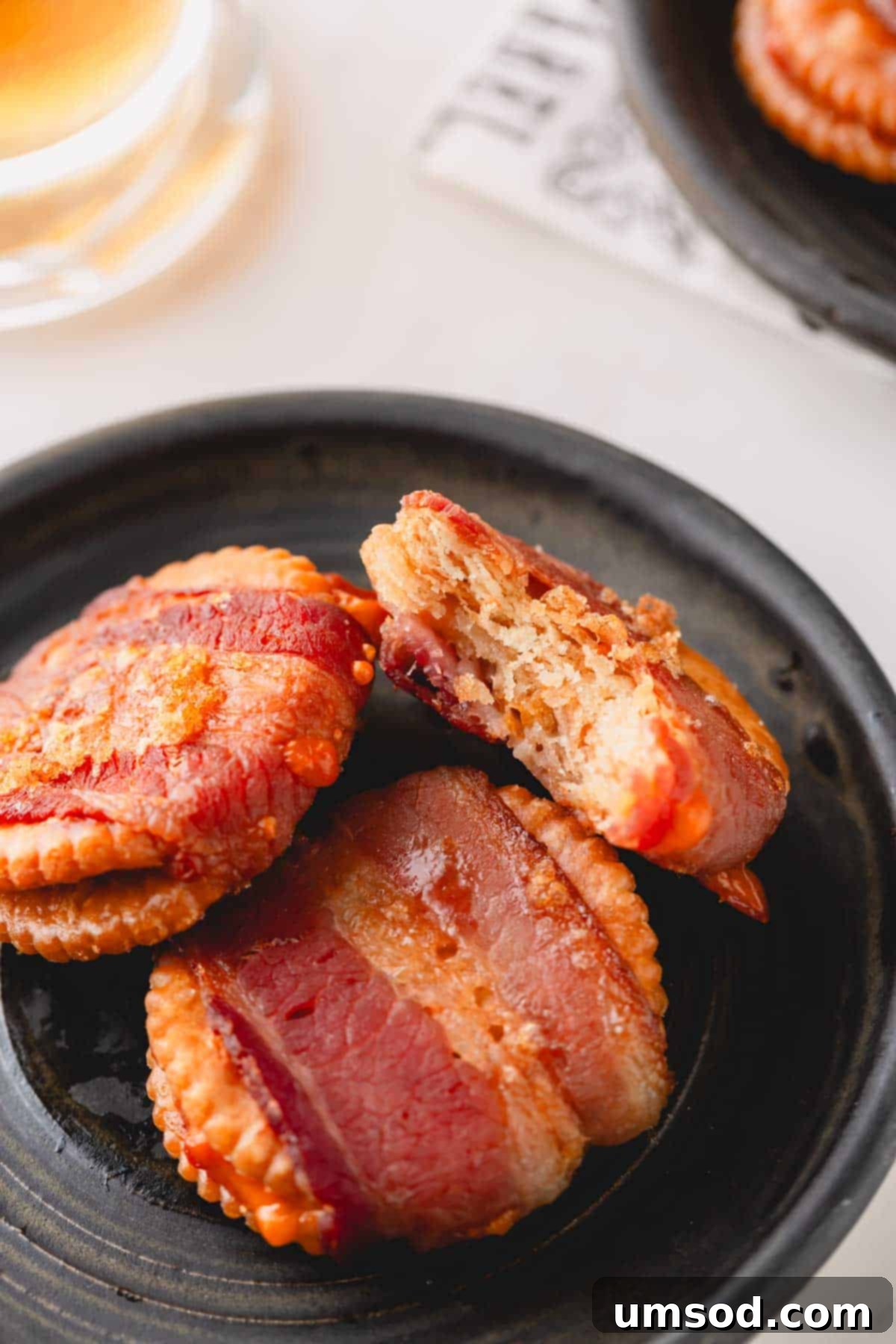 Smoky Bacon Cheese Bites 10 Three perfectly baked cheesy bacon crackers on a white plate, one with a bite taken out, highlighting the irresistible nature.