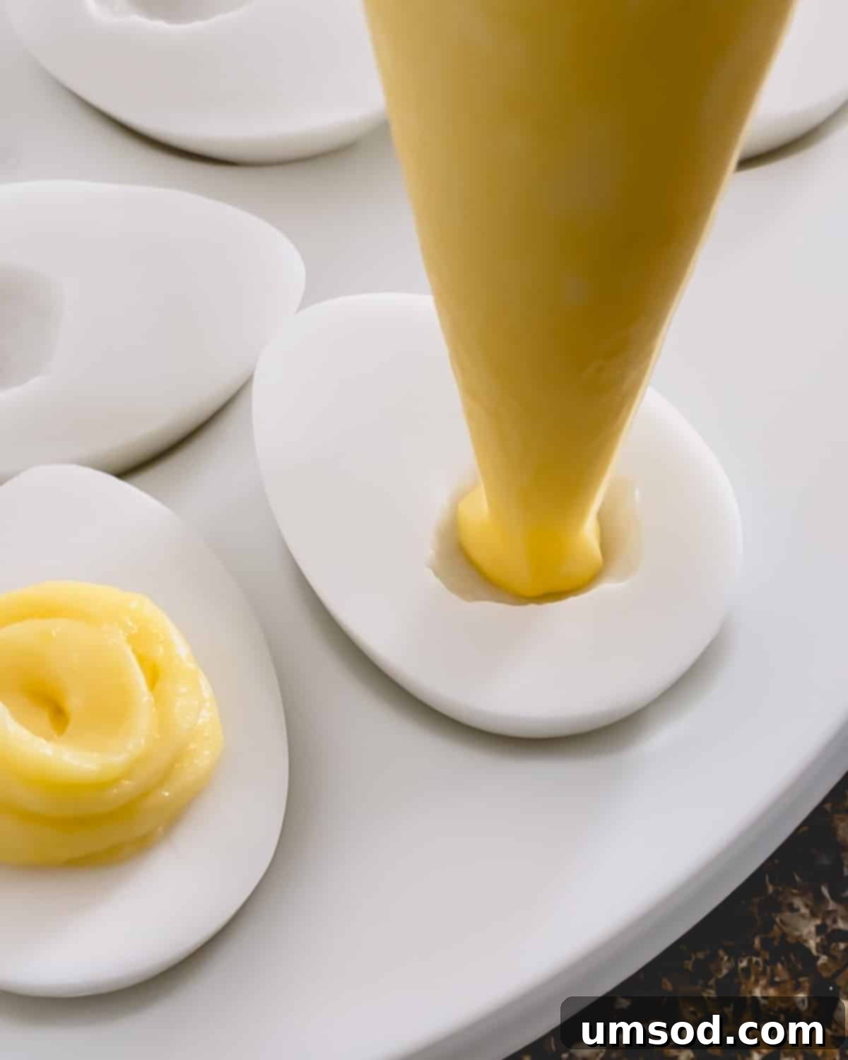 A perfectly piped yellow pineapple filling nestled into the white, egg-shaped coconut pudding.