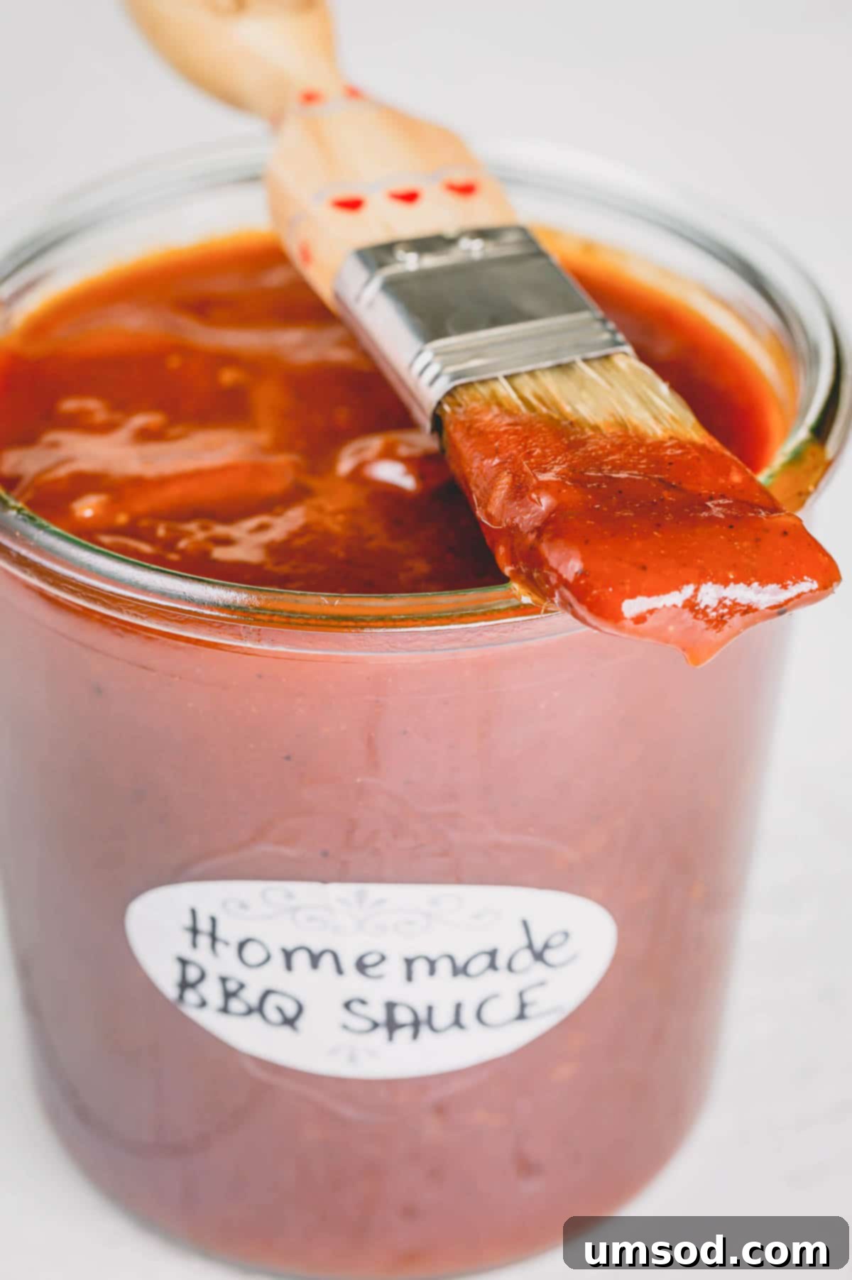 Easy Homemade BBQ Sauce Recipe 2 A beautifully presented jar of homemade BBQ sauce with a basting brush, ready for summer grilling.
