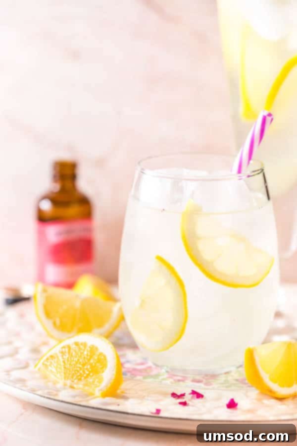Close-up of a glass of refreshing rose lemonade garnished with fresh lemon slices and edible rose petals, ready for a summer party.