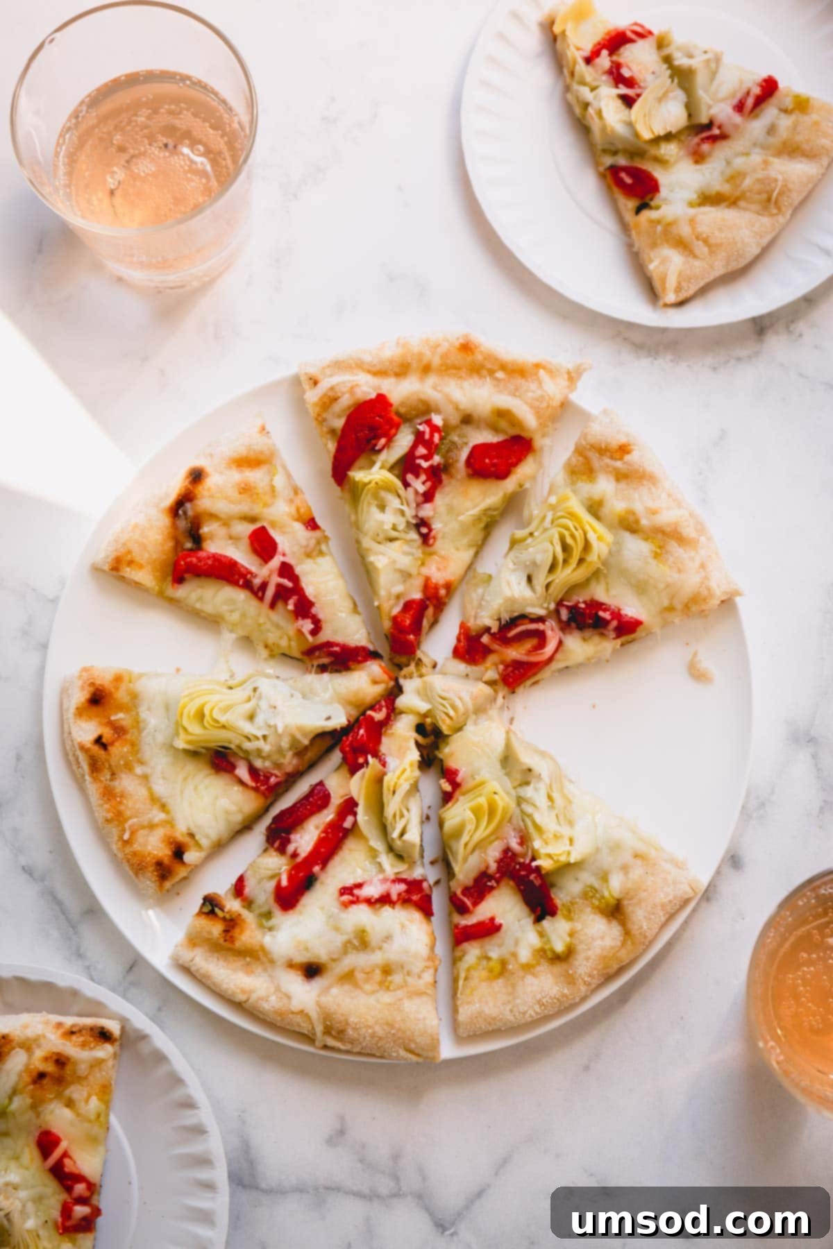 A perfectly grilled artichoke pizza, freshly sliced and ready to serve on a white plate, showcasing its golden crust and delicious toppings.