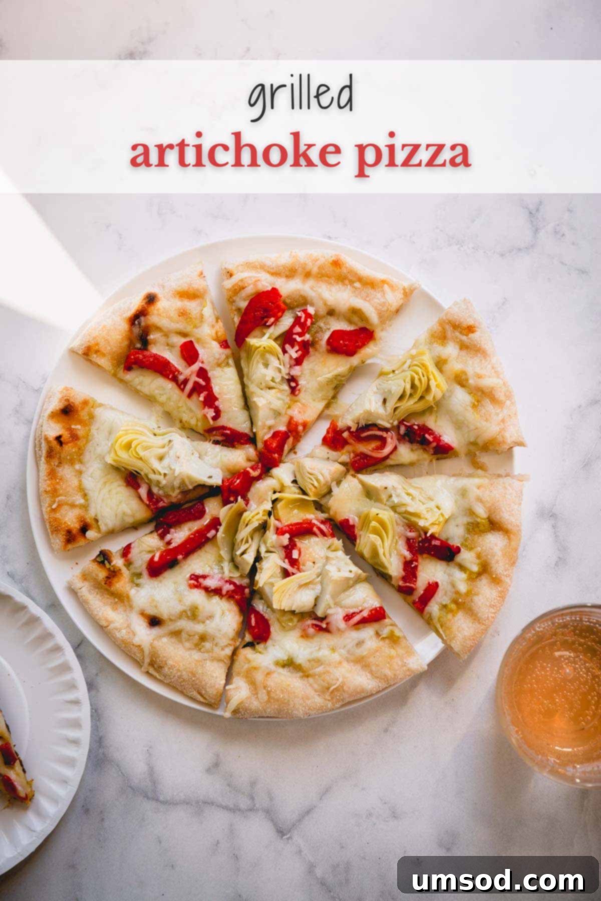 A beautifully sliced grilled artichoke pizza, garnished with fresh herbs, resting on a rustic white plate with a fork.