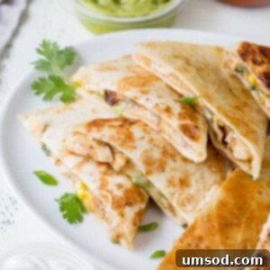 Effortless 30-Minute Cheesy Chicken Quesadillas 8 Close-up of a finished cheesy chicken quesadilla, sliced and ready to eat, with melted cheese and chicken visible.
