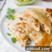 Effortless 30-Minute Cheesy Chicken Quesadillas 9 Freshly chopped cilantro and a lime wedge, garnishes typically served with cheesy chicken quesadillas.
