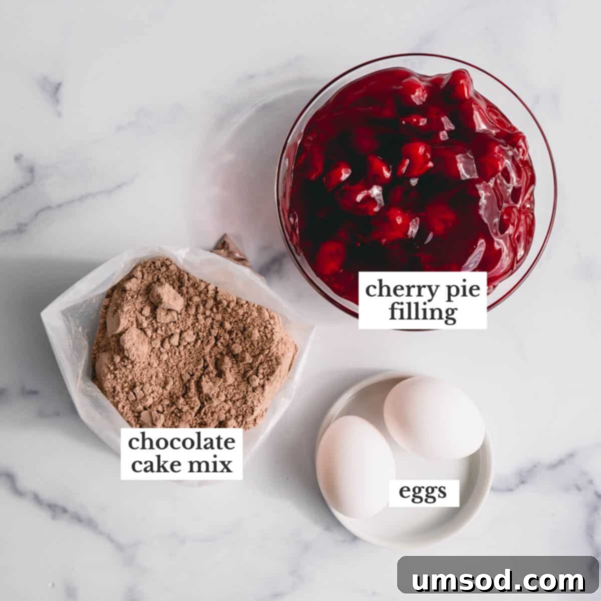 Three core ingredients for chocolate cherry cake laid out: two large eggs, a box of devil's food cake mix, and a can of cherry pie filling.
