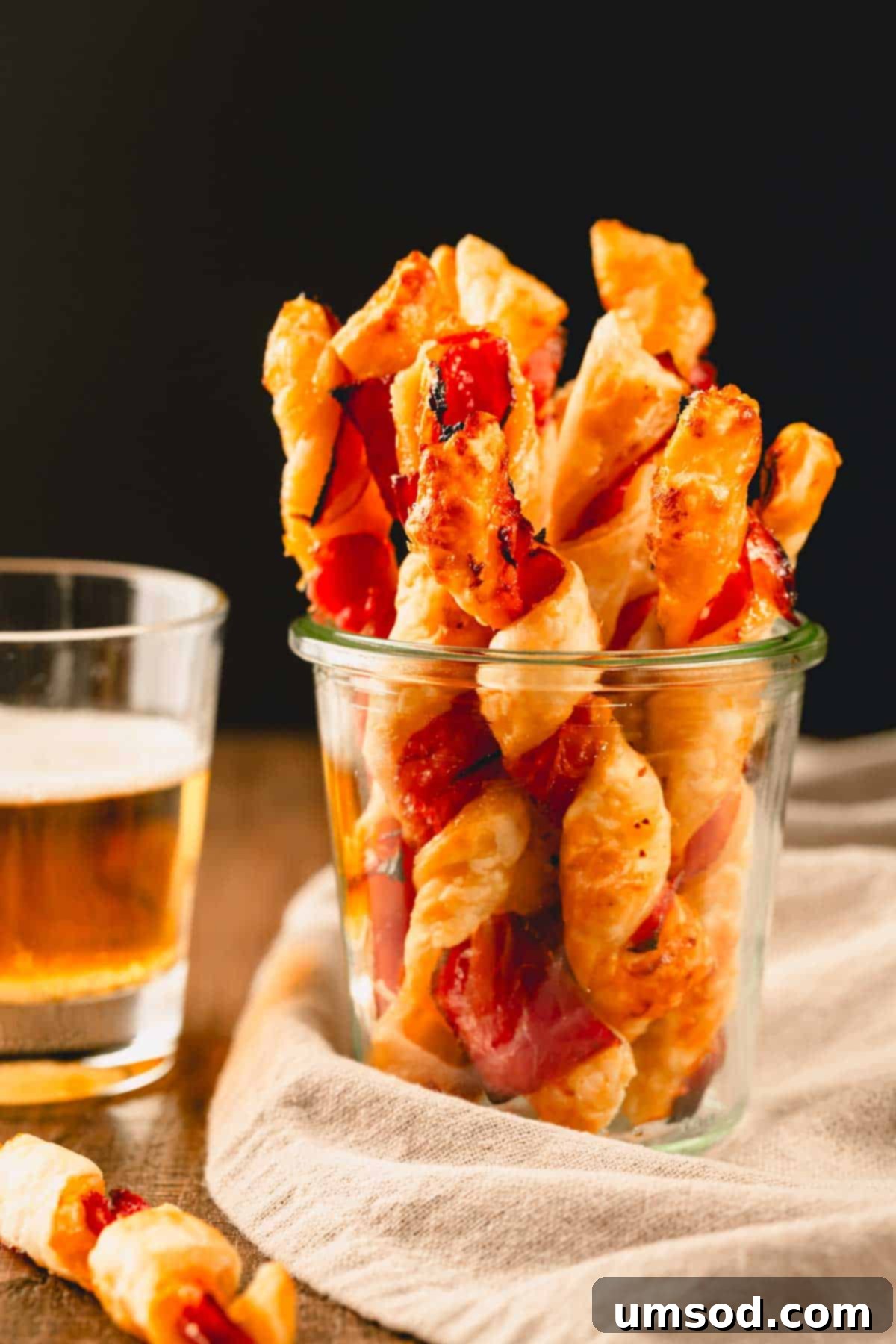 Savory puff pastry twists in a glass cup, highlighting their golden-brown perfection.