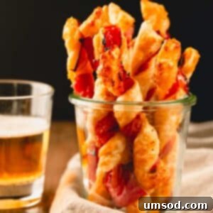 Savory puff pastry twists in a glass cup.