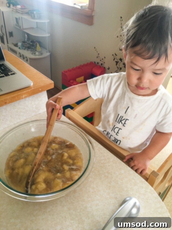 Toddler Grant happily mixing ingredients in a bowl, making banana bread with his mom.
