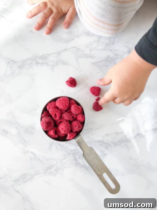 Toddler Grant reaching for freeze-dried raspberries, his favorite snack, during a food photoshoot.