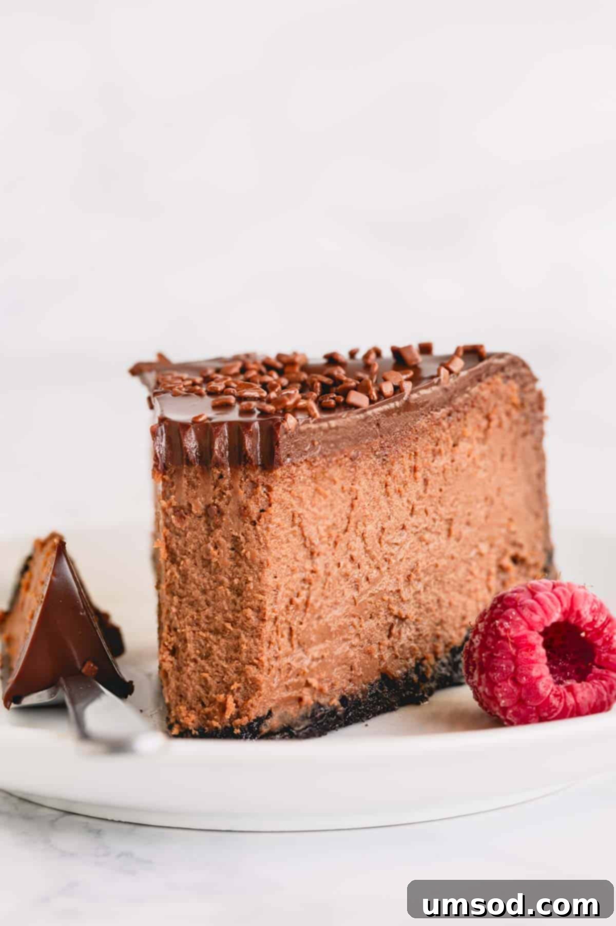 A slice of supreme chocolate cheesecake topped with chocolate ganache. 