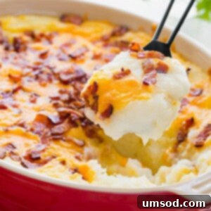Ultimate Loaded Potato Bake 8 A serving spoon lifting a scoop of loaded mashed potato casserole from a dish.
