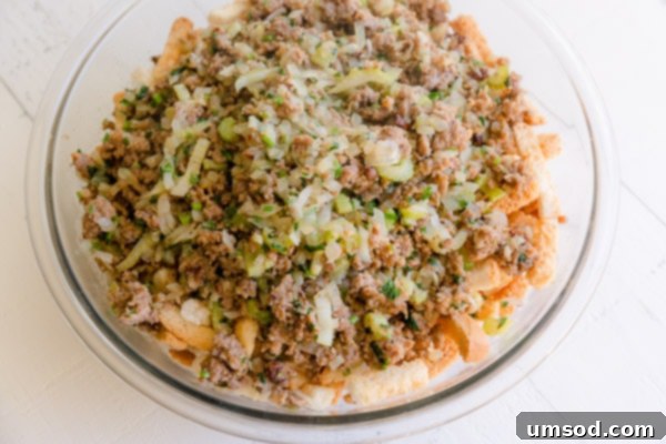 A large bowl filled with Instant Pot sausage stuffing ingredients: browned sausage, sautéed vegetables, and bread cubes.