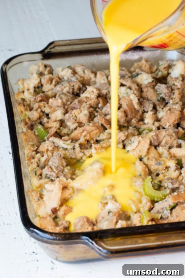 Stuffing Revival Breakfast Bake 4 Egg mixture being poured over a layer of sausage stuffing in a baking dish, illustrating a step in making breakfast casserole.