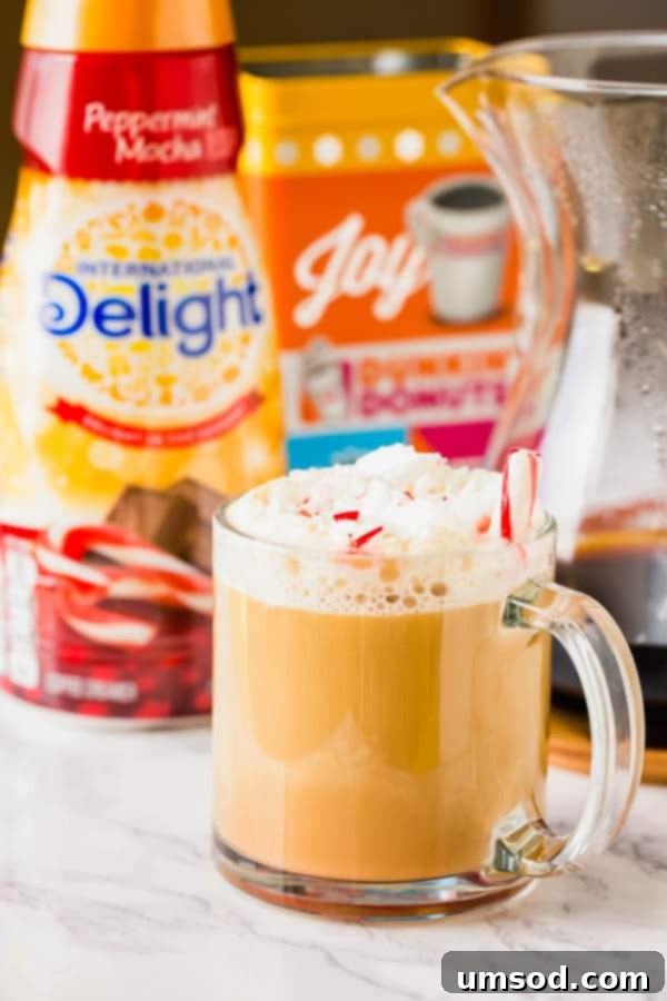 Sweet Crust Coffee 5 A glass mug of Peppermint Mocha coffee, topped with whipped cream, next to a bottle of International Delight Peppermint Mocha creamer.