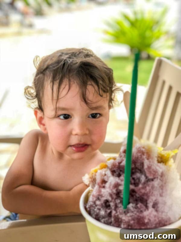 Toddler joyfully playing in the shallow end of a resort pool in Kauai