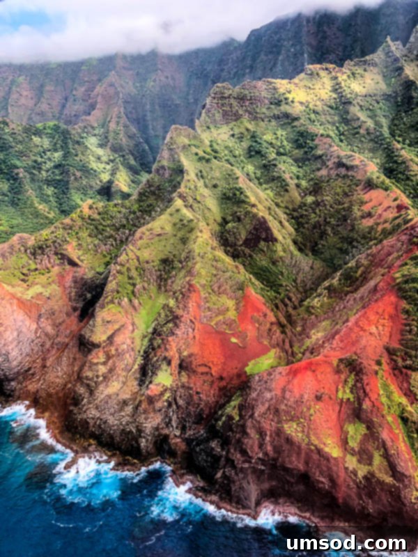 Toddler Friendly Kauai Exploring the Garden Isle 10 Stunning waterfall cascading down a green cliffside in Kauai, seen from above