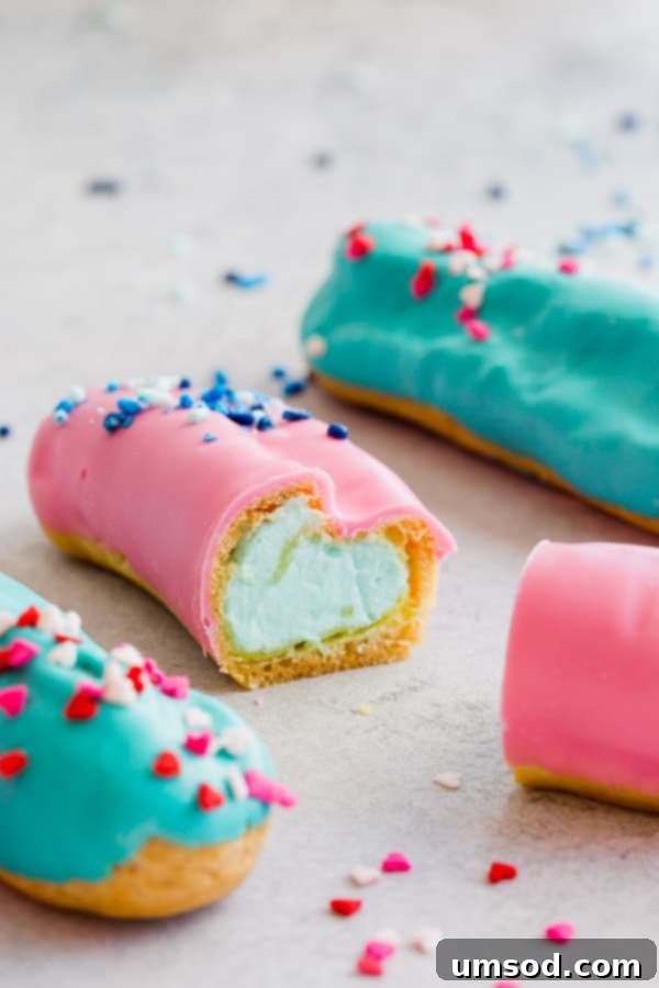 Pink or Blue Eclair Mystery 4 An assortment of blue and pink gender reveal eclairs arranged on a platter, adorned with sprinkles.