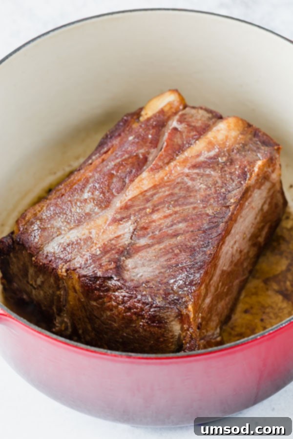Searing a chuck roast in a hot Dutch oven creates a delicious browned crust, crucial for developing deep, rich flavors in pot roast.