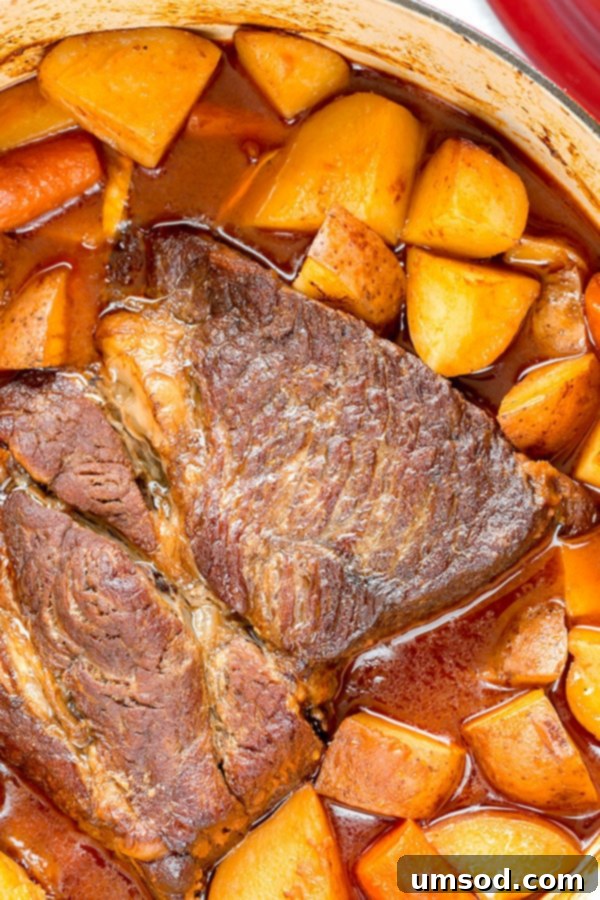 A perfectly cooked pot roast, tender beef and vegetables submerged in rich gravy, after hours of slow cooking in a Dutch oven.