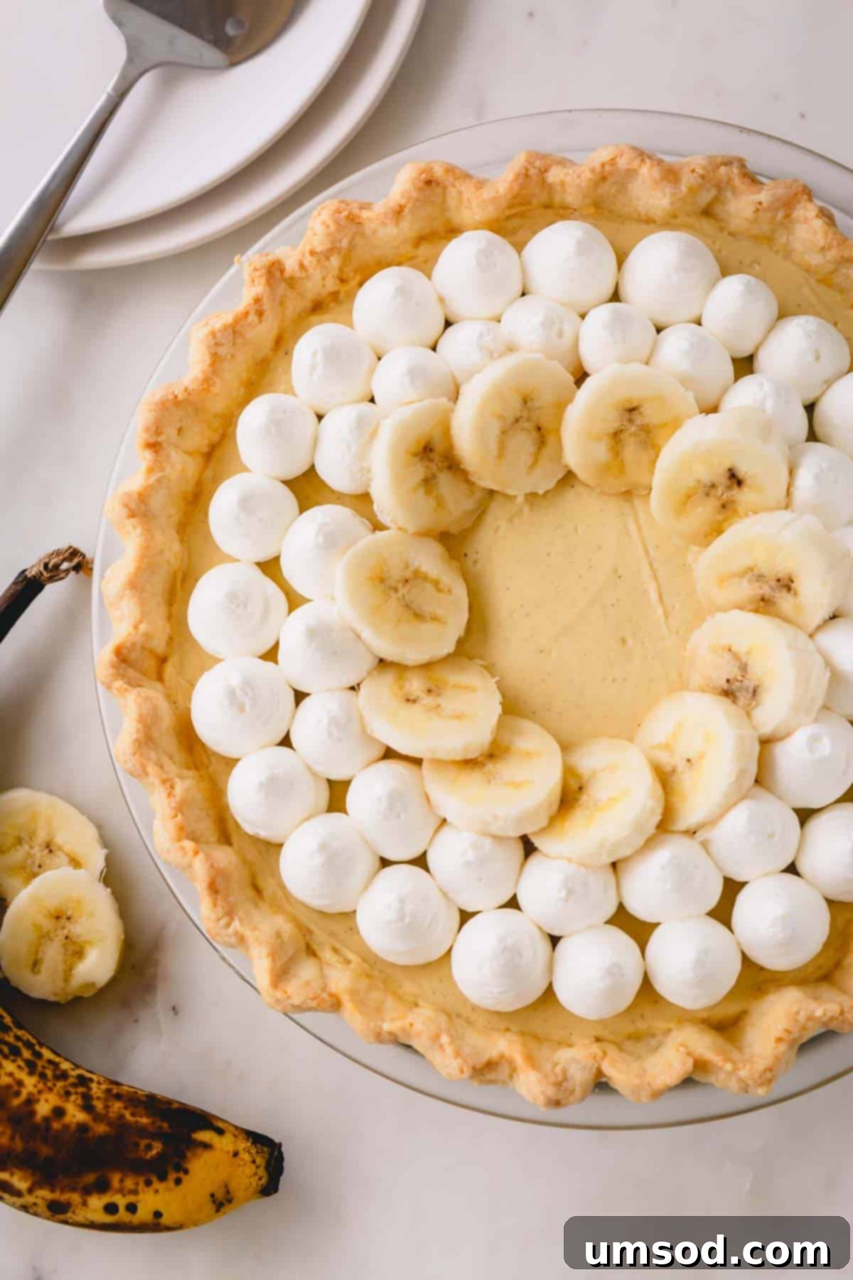 Banana cream pie decorated with dollops of whipped cream and banana slices.