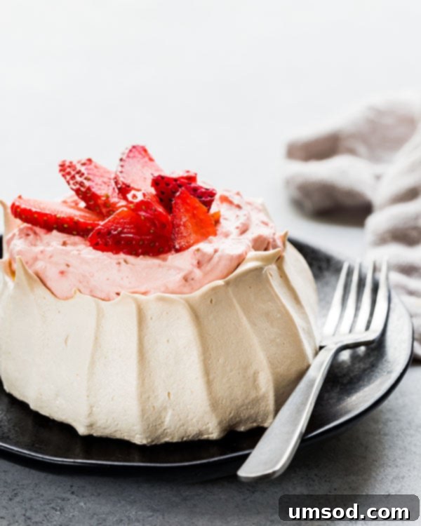 Luscious Strawberry Pavlova Bites 8 A beautifully presented mini strawberry pavlova on a plate, with a fork resting beside it, inviting a taste.