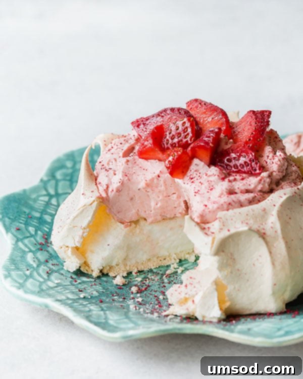 Luscious Strawberry Pavlova Bites 9 A delectable mini strawberry pavlova with a slice already removed, highlighting its perfect interior and creamy filling.