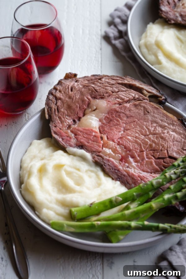 Ultimate Prime Rib Perfection 7 A beautifully plated serving of boneless prime rib, accompanied by creamy mashed potatoes, tender asparagus, and glasses of red wine on the side.