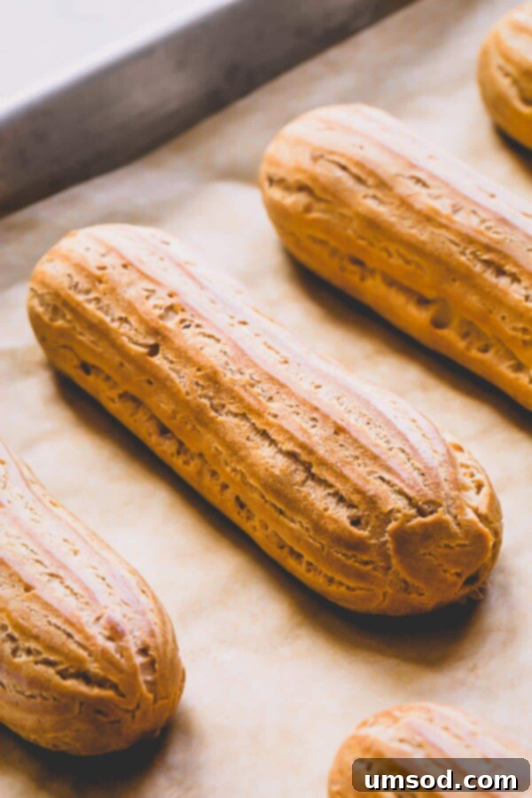 Freshly baked golden brown choux pastry shells cooling on a rack, ready for filling.