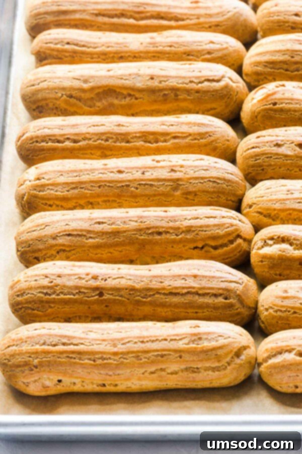 A tray of perfectly golden choux pastry shells with a beautiful rise, cooling after baking.