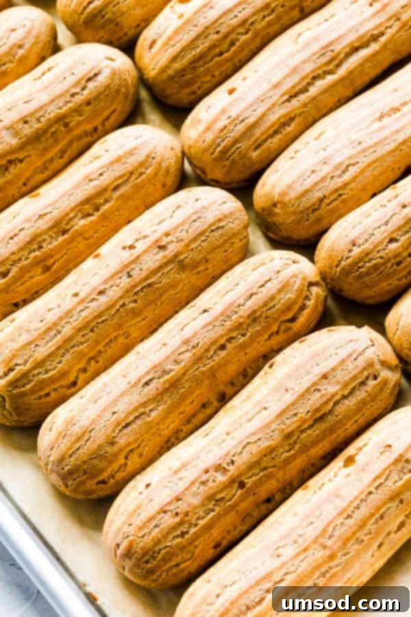 Expertly piped raw choux pastry dough on a baking sheet, ready for the oven.