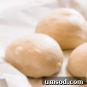 Effortless Homemade Pizza Dough 17 Two pizza dough balls on parchment paper.