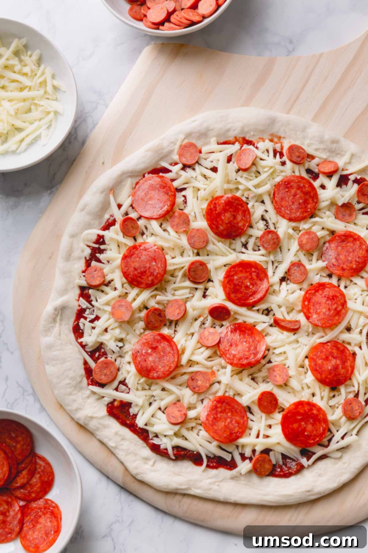Effortless Homemade Pizza Dough 3 An unbaked pizza, generously topped with melted cheese and classic pepperoni, ready for the oven.