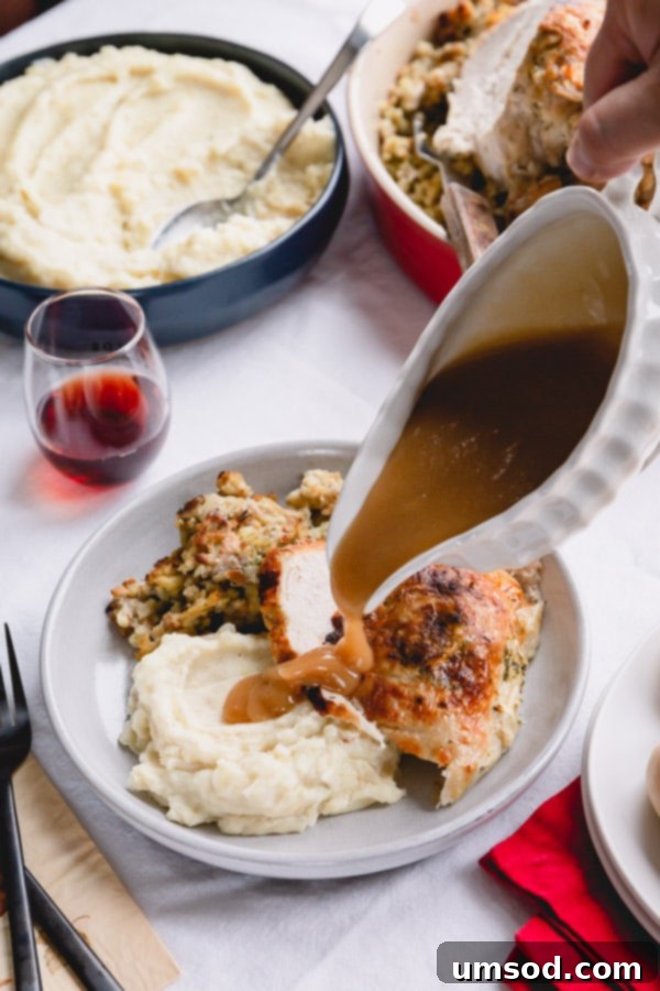 Rich, homemade gravy being generously poured over a serving of savory stuffing, creamy mashed potatoes, and tender turkey breast on a festive plate. 