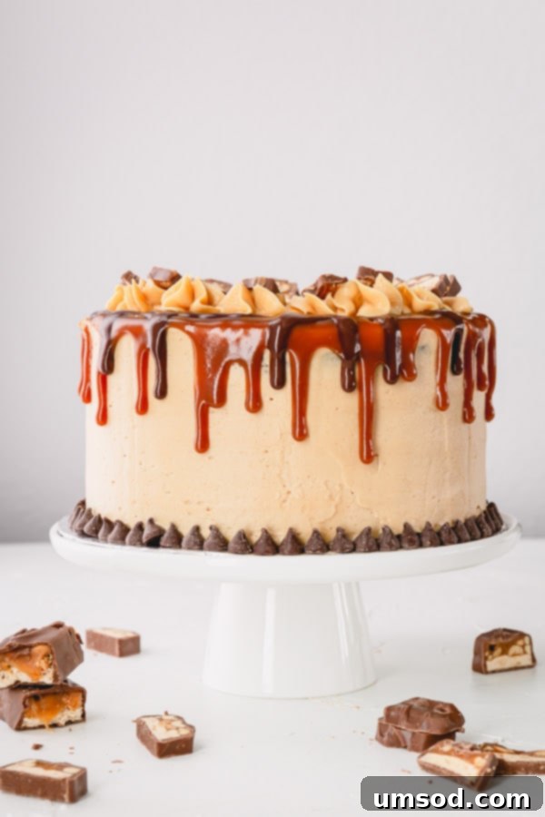 Chocolate Peanut Caramel Dream Cake 15 A stunning full view of the Snickers cake, elaborately decorated with elegant caramel and chocolate drips, topped with Snickers bar slices.