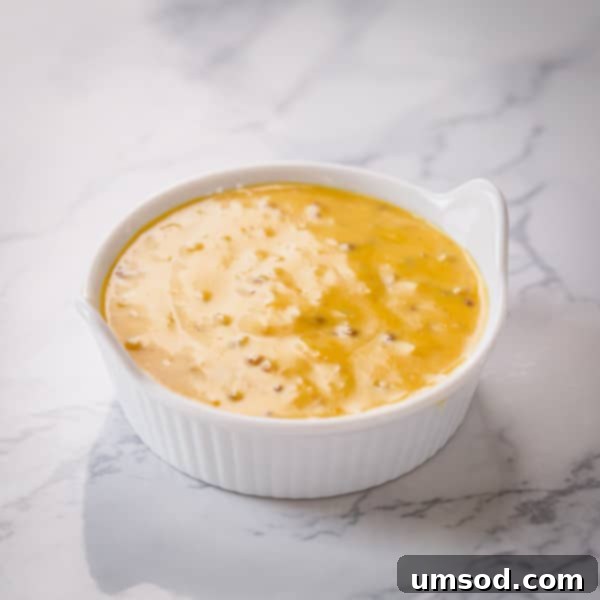 Dip into Delight: 5 Mouthwatering Sauce Recipes 4 Close-up shot of creamy honey mustard sauce in a white bowl, garnished with a sprinkle of paprika.