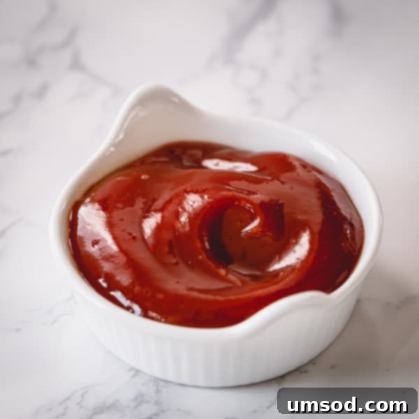 Dip into Delight: 5 Mouthwatering Sauce Recipes 7 A small bowl of vibrant red spicy ketchup, ready for dipping, with a hint of sriracha visible.