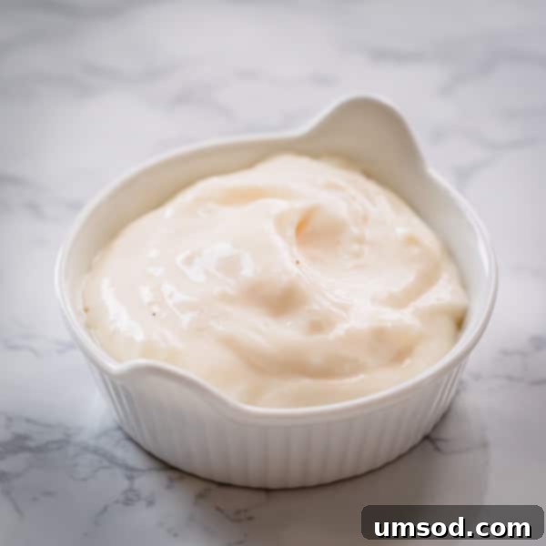 Dip into Delight: 5 Mouthwatering Sauce Recipes 10 A bowl of creamy garlic aioli, ready to be enjoyed with a side of fresh artichoke leaves.